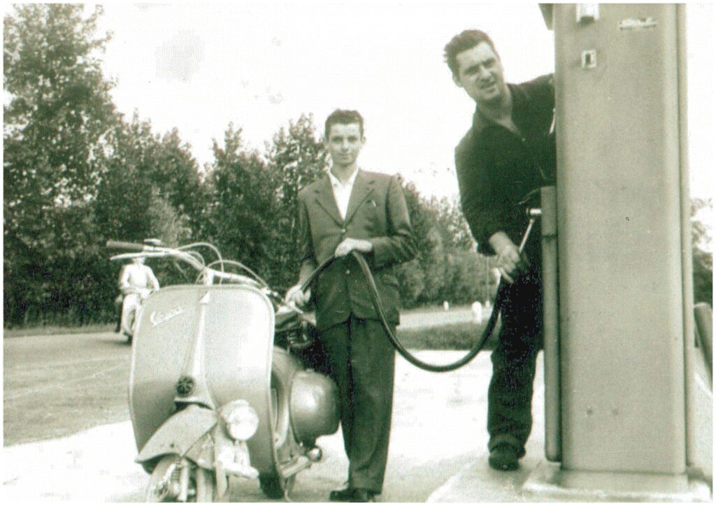 Due uomini fanno benzina a una Vespa